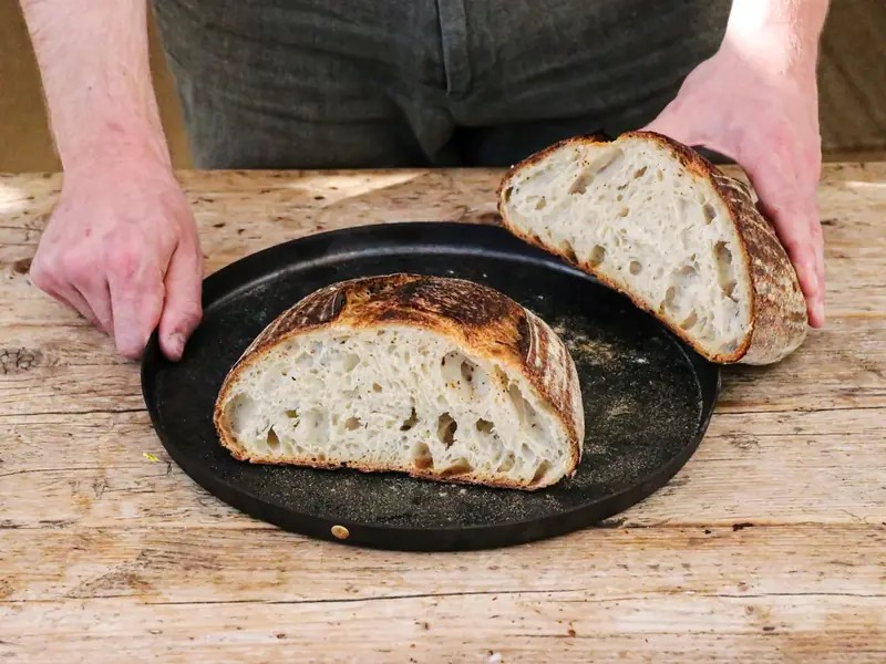 A baker with a freshly cut sourdough loaf